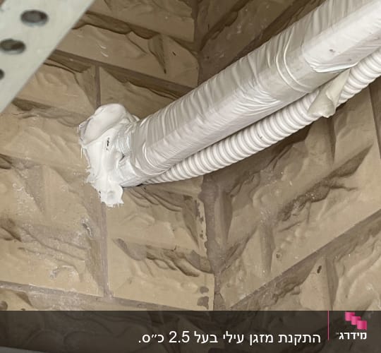 צינור מיזוג אוויר עטוף בבידוד לבן על קיר לבנים